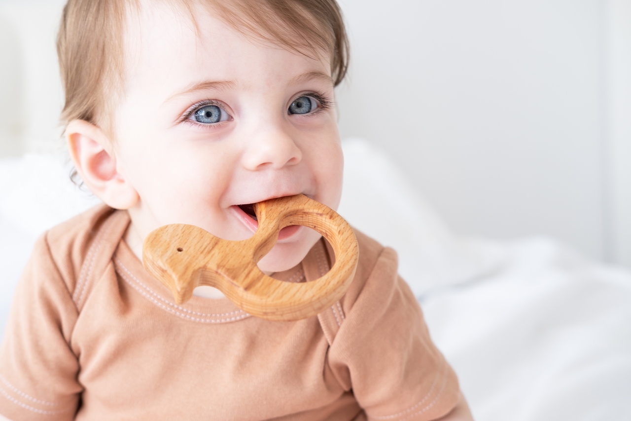Happy baby chewing on wooden toy indoors 2026 01 06 10 39 46 utc 1